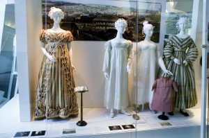 Display case with four mannequins with dresses and paper hairstyles 